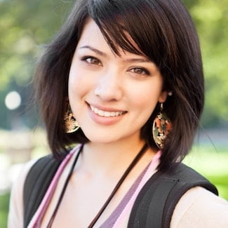 A woman with short dark hair smiling outside